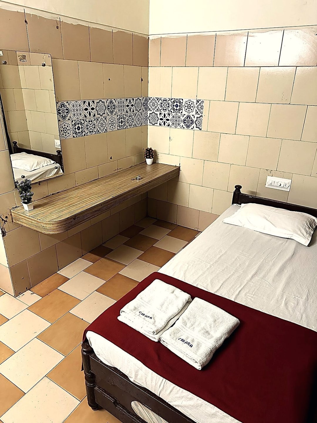 Single room at Cibara Comforts with a made bed, folded towels and a tiled washbasin counter